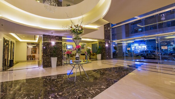 A modern lobby with a central glass table, marble flooring, and a large potted plant. - Imperial Suites Hotel (Doha)