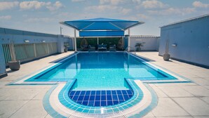 A swimming pool with a blue canopy, lounge chairs, and potted plants. - Imperial Suites Hotel (Doha)