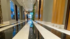 A long, polished corridor with reflective flooring, flanked by walls with vertical wooden panels and recessed lighting. - Imperial Suites Hotel (Doha)