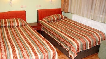 Two single beds with striped bedding, a wooden floor, and a radiator.