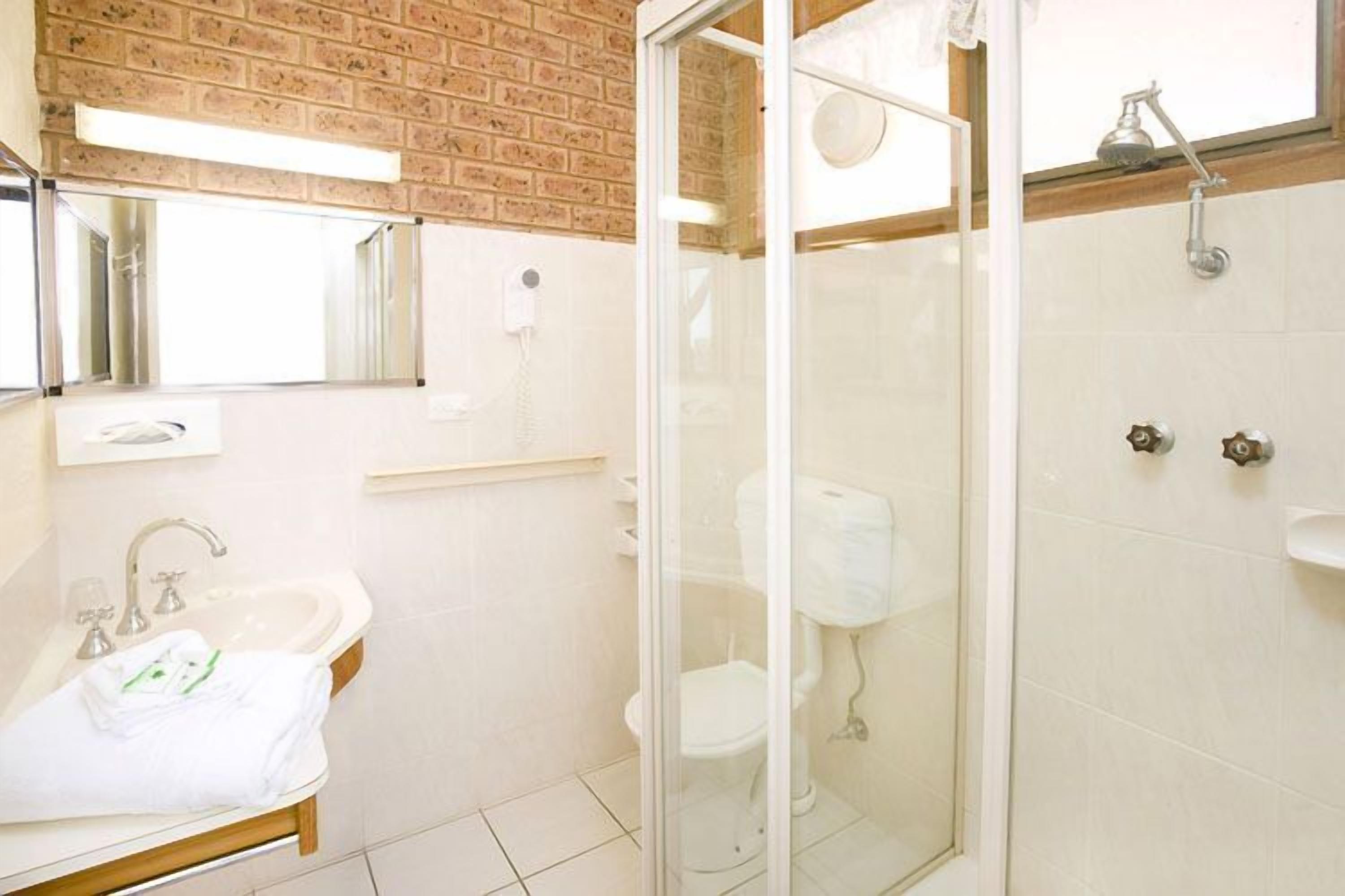 A bathroom with a glass-enclosed shower, a sink with a mirror above it, and a toilet.
