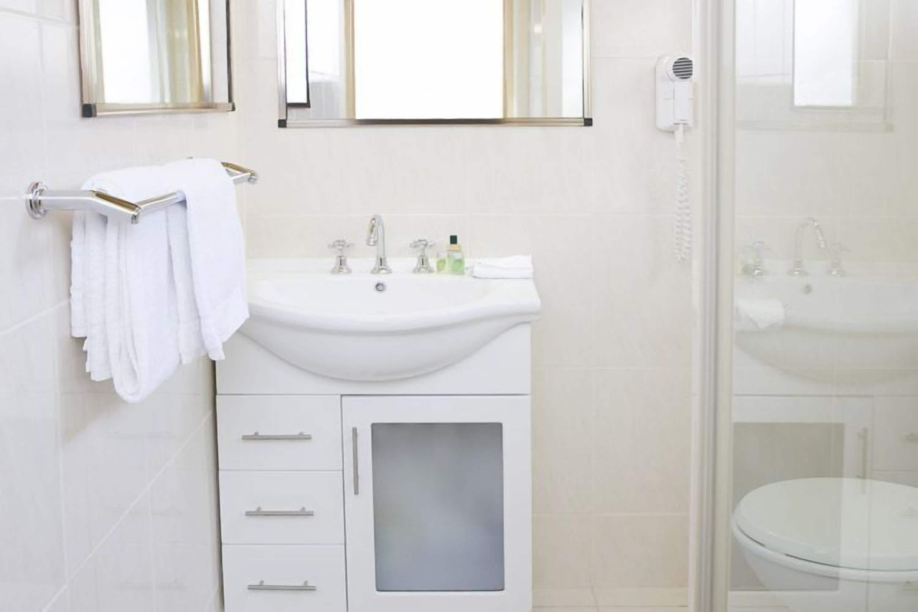 A bathroom with a white sink, mirror, and towel rack.