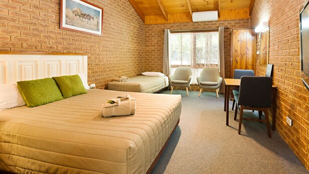A room with a large bed, two smaller beds, a desk, and a chair. - Beechworth Carriage Motor Inn (Beechworth)