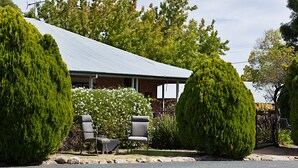 A house with a metal roof, two chairs, and a small table in the front yard. - Beechworth Carriage Motor Inn (Beechworth)