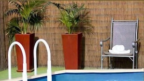 A swimming pool with two potted plants and a chair. - Beechworth Carriage Motor Inn (Beechworth)