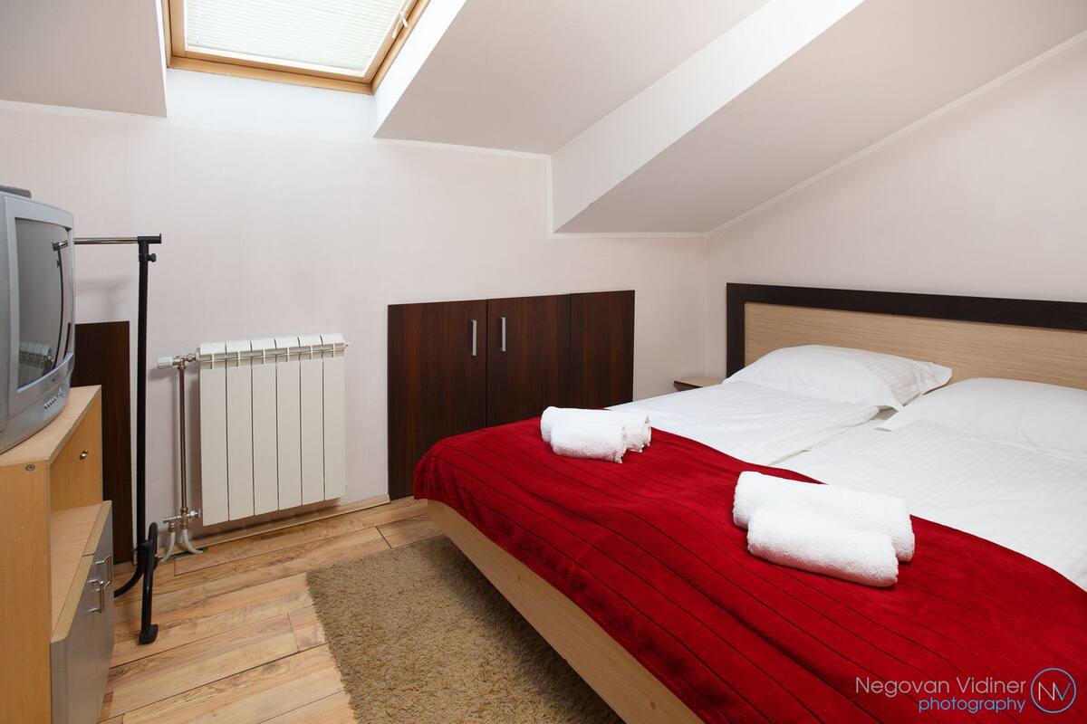 A bedroom with a bed, a TV, a radiator, and a wardrobe.