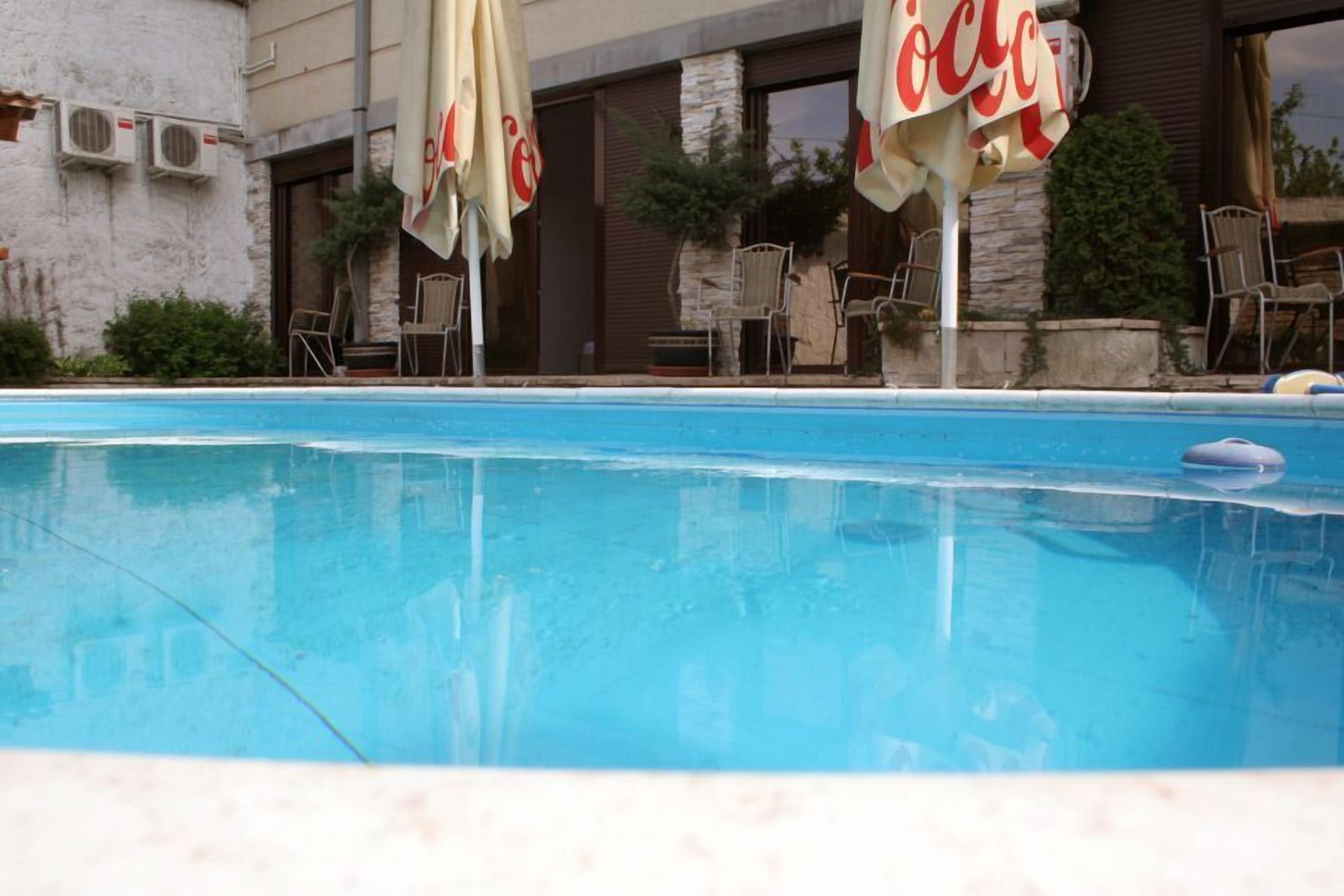 A swimming pool with Coca-Cola branded umbrellas and chairs.