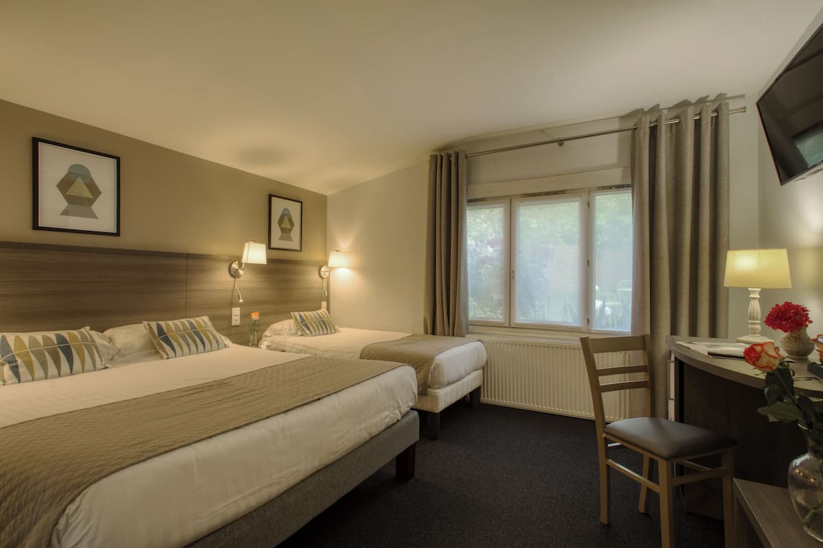 Habitación de hotel con dos camas, un escritorio, una silla, una ventana con cortinas y lámparas fijadas a la pared.