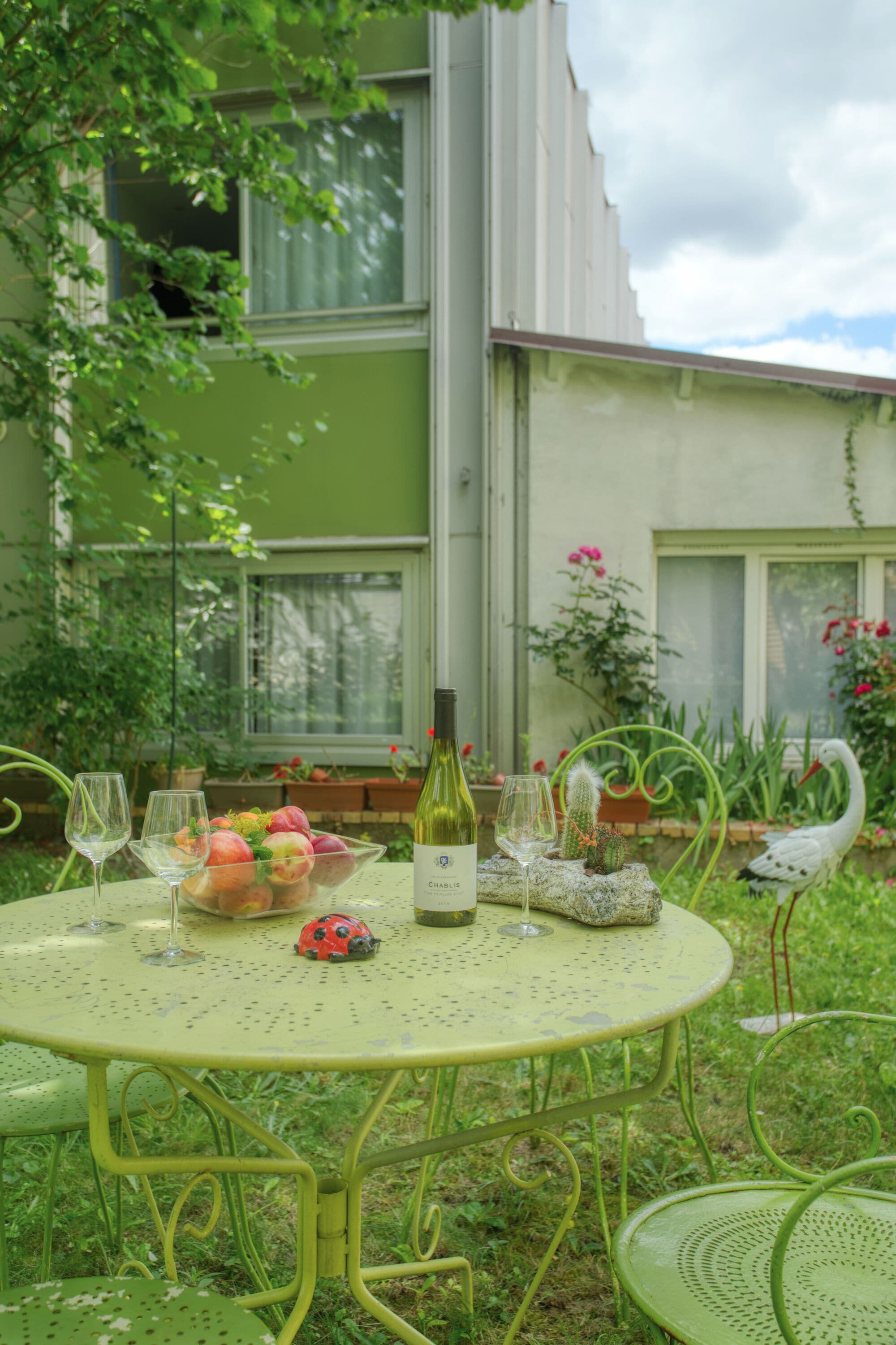 Une table ronde avec une bouteille de vin, des verres et un saladier de fruits.