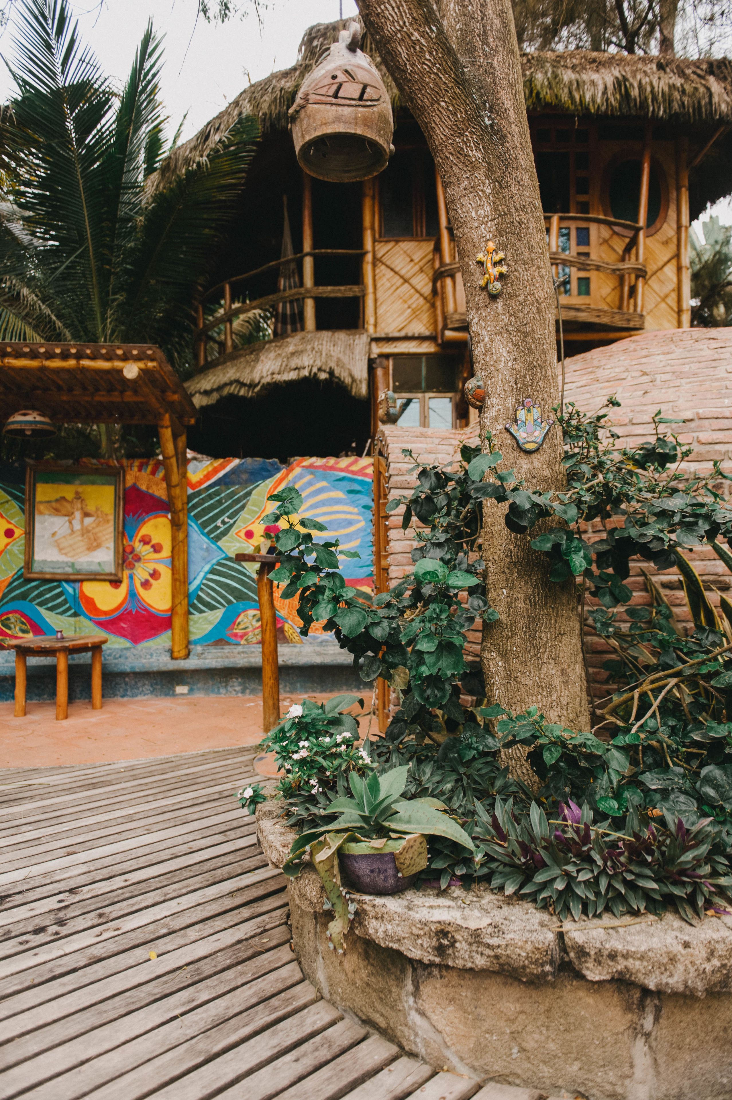 A wooden structure with a thatched roof, a wooden bench, and a colorful mural on the wall.