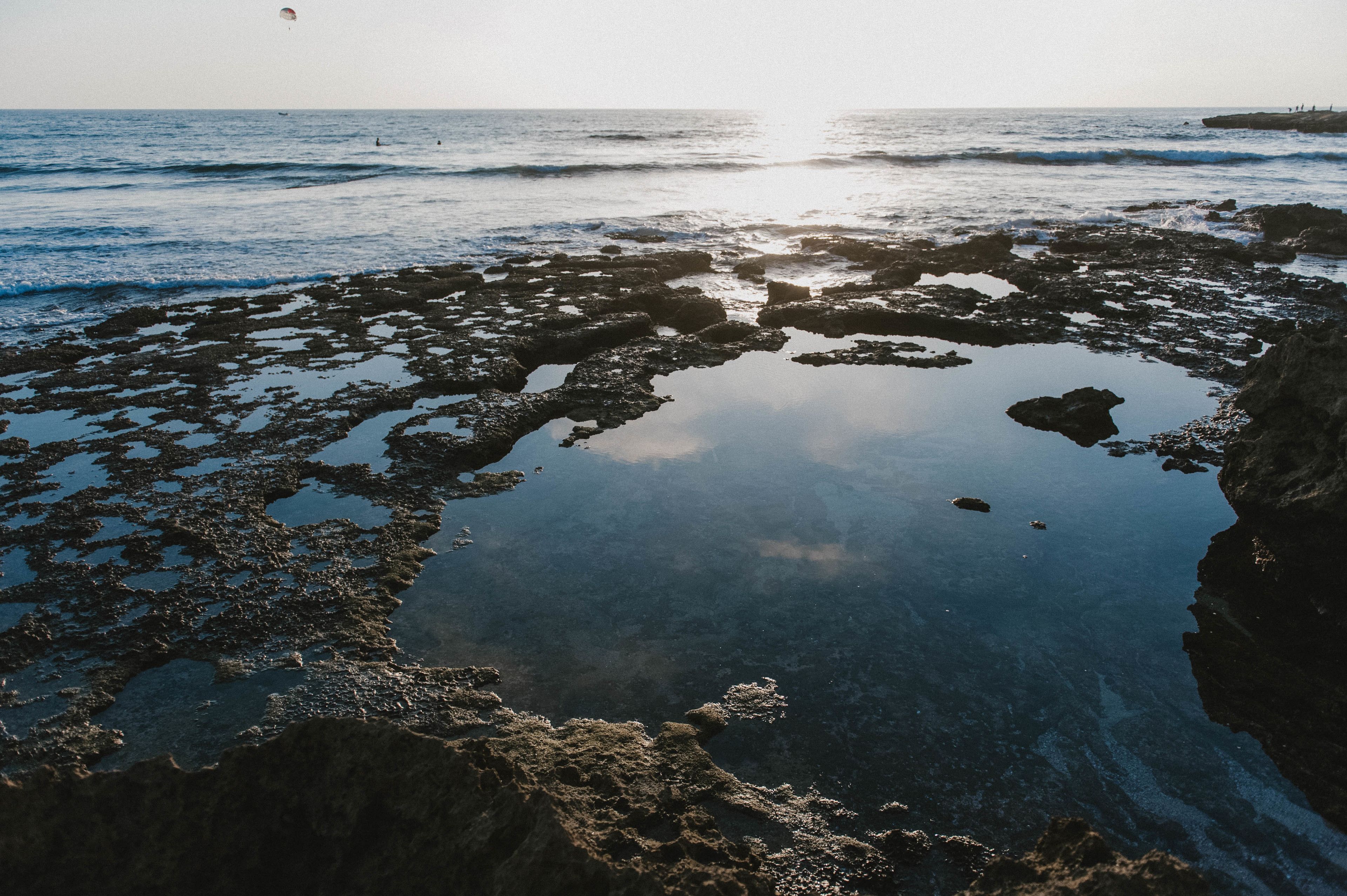 Una costa rocosa con aguas claras que reflejan el cielo.