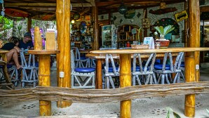 Un espacio de estar al aire libre rústico con mesas y sillas de madera, rodeado por una cerca de madera.