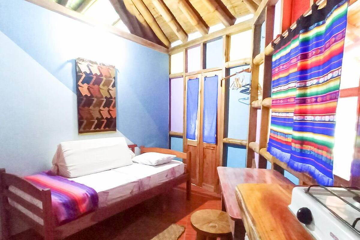 A small, cozy room with a bed, a table, and a stove.