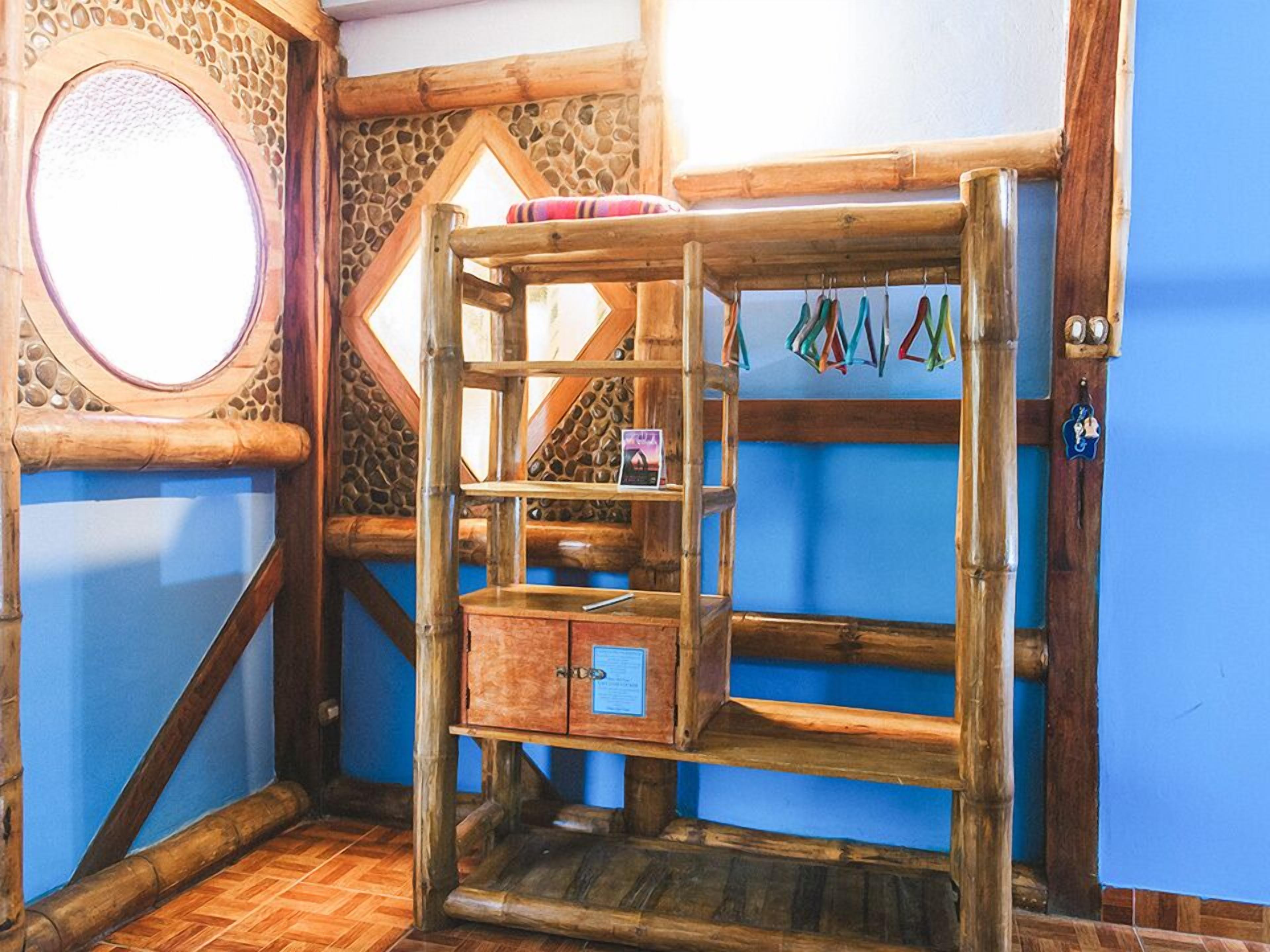 Una habitación rústica de madera con un ventanal circular, un banco de madera y una estantería con objetos de colores.