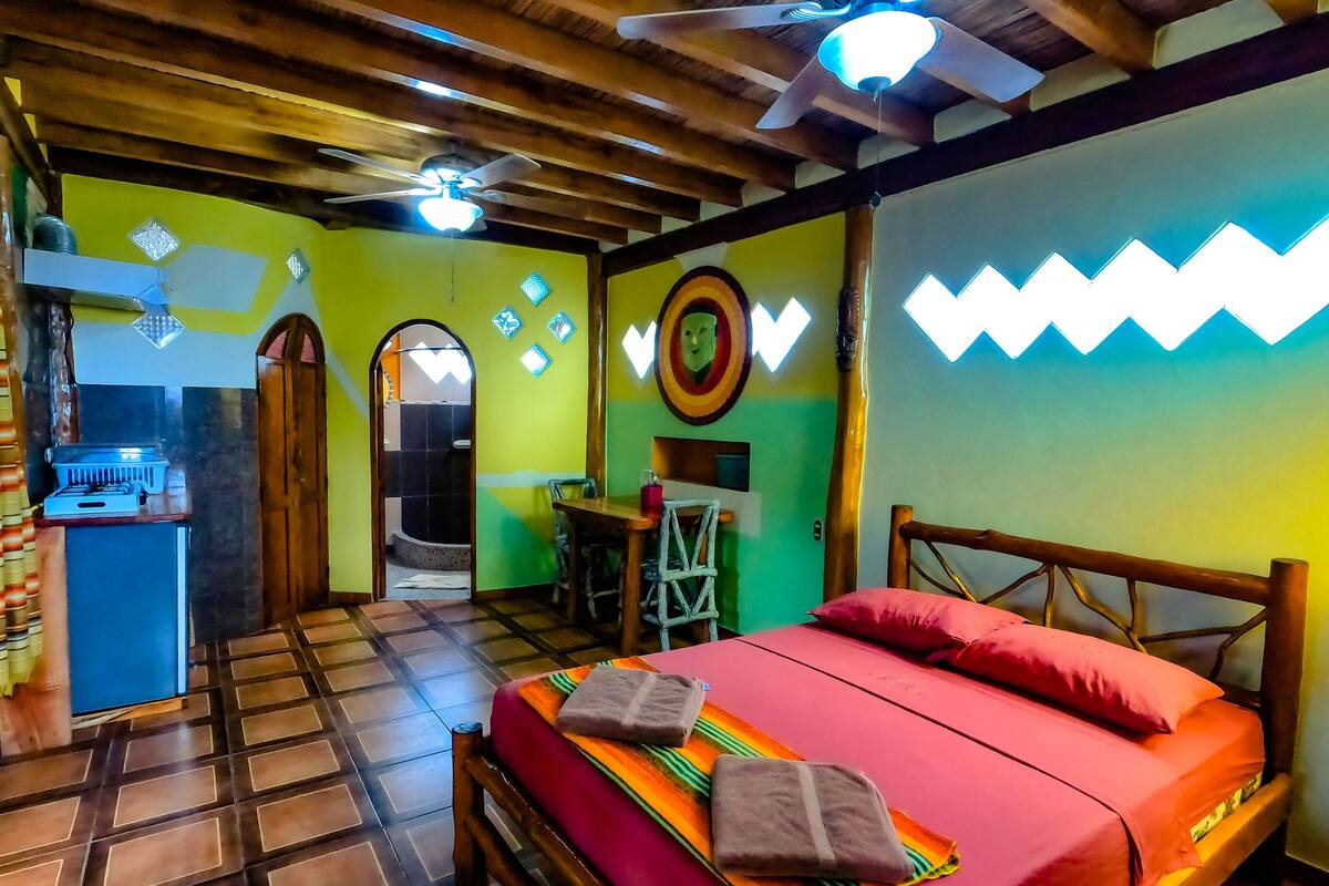 A room with a bed, a desk, and a ceiling fan.