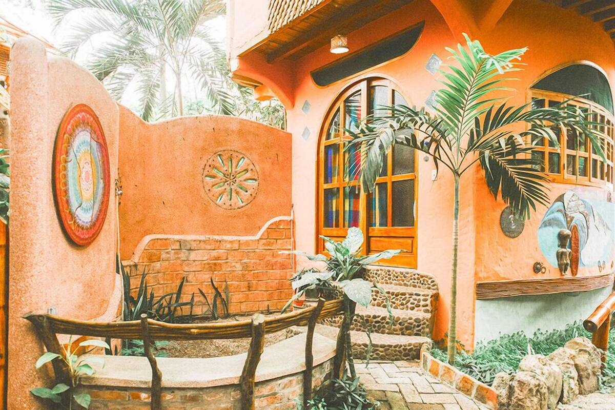 A courtyard with a brick wall, a wooden bench, a small table, and a potted plant.