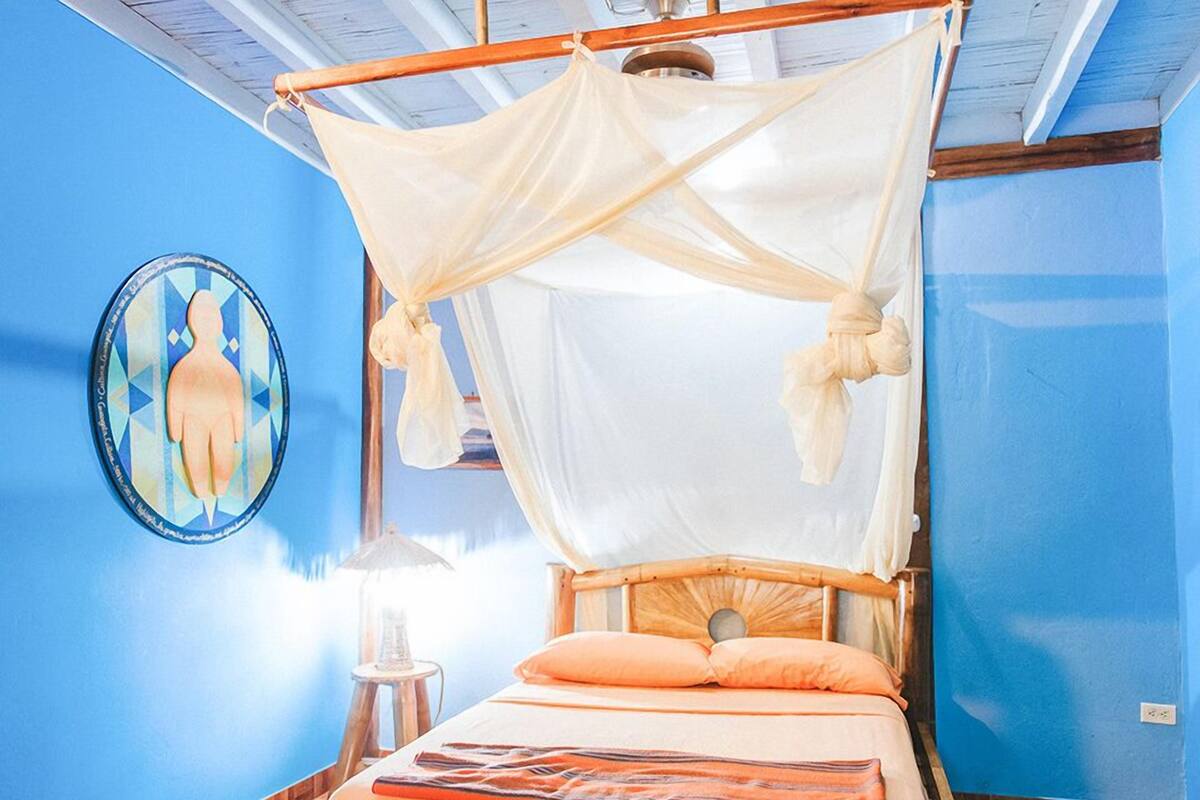 A bed with a canopy, a wall clock, and a lamp.