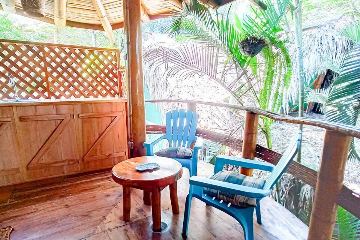 A wooden deck with a table and chairs, a wooden door, and a view of palm trees.