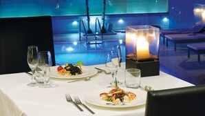 Una mesa de comedor servida con platos de mariscos, copas de vino y un centro de mesa con velas.
