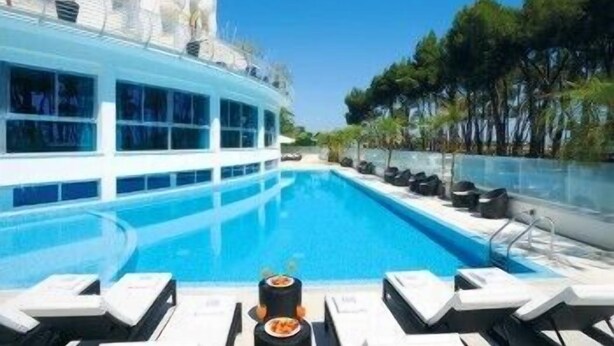 Zona de piscina con sillas de descanso y un bar junto a la piscina.