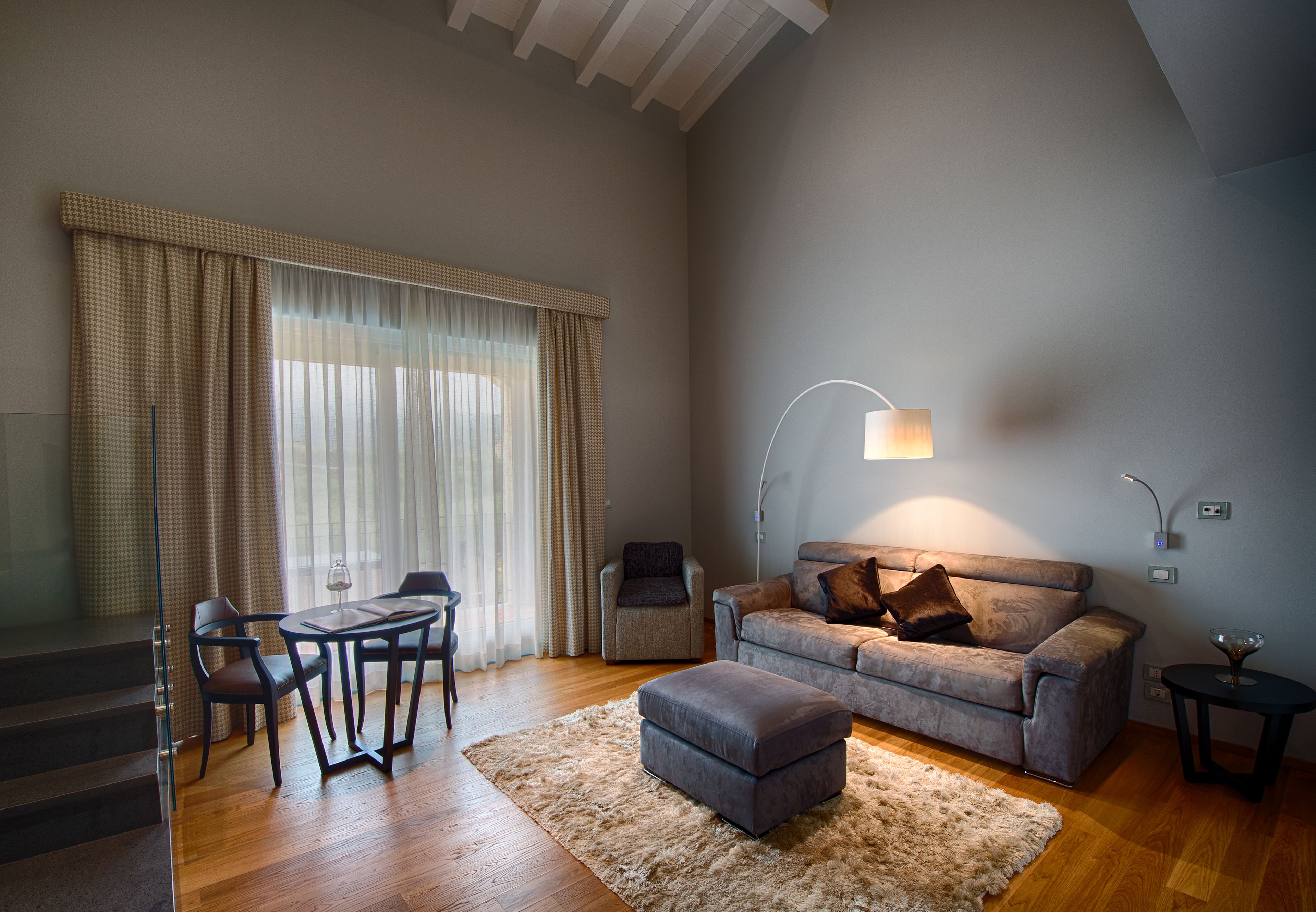 A modern living room with a sofa, ottoman, and a dining area with a table and chairs.