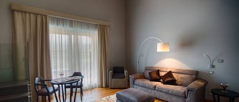 A modern living room with a sofa, ottoman, and a dining area with a table and chairs.