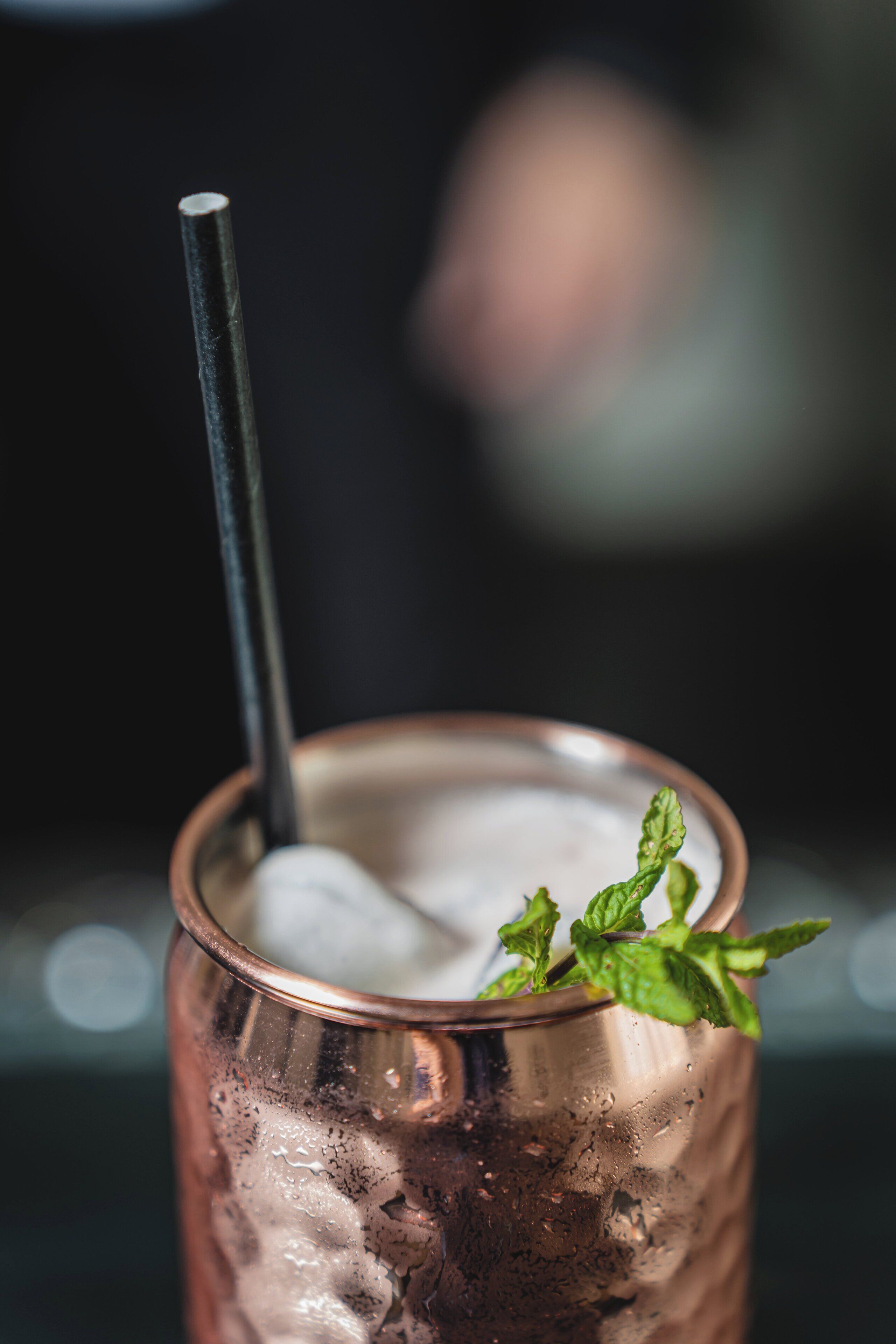 Un vaso de cobre con hielo y una ramita de menta.