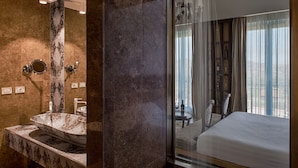 A modern bathroom with a large marble sink, a glass shower enclosure, and a view of a bedroom with a bed and a table. - Villa Neri Resort & Spa (Linguaglossa)
