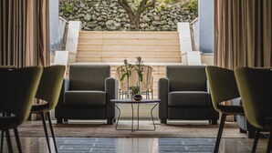 A modern interior with a seating area, a stone wall, and a view of a garden. - Villa Neri Resort & Spa (Linguaglossa)