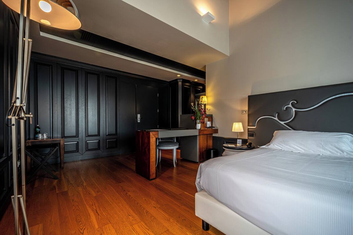 A modern hotel room with a large bed, a desk, and a shower area.