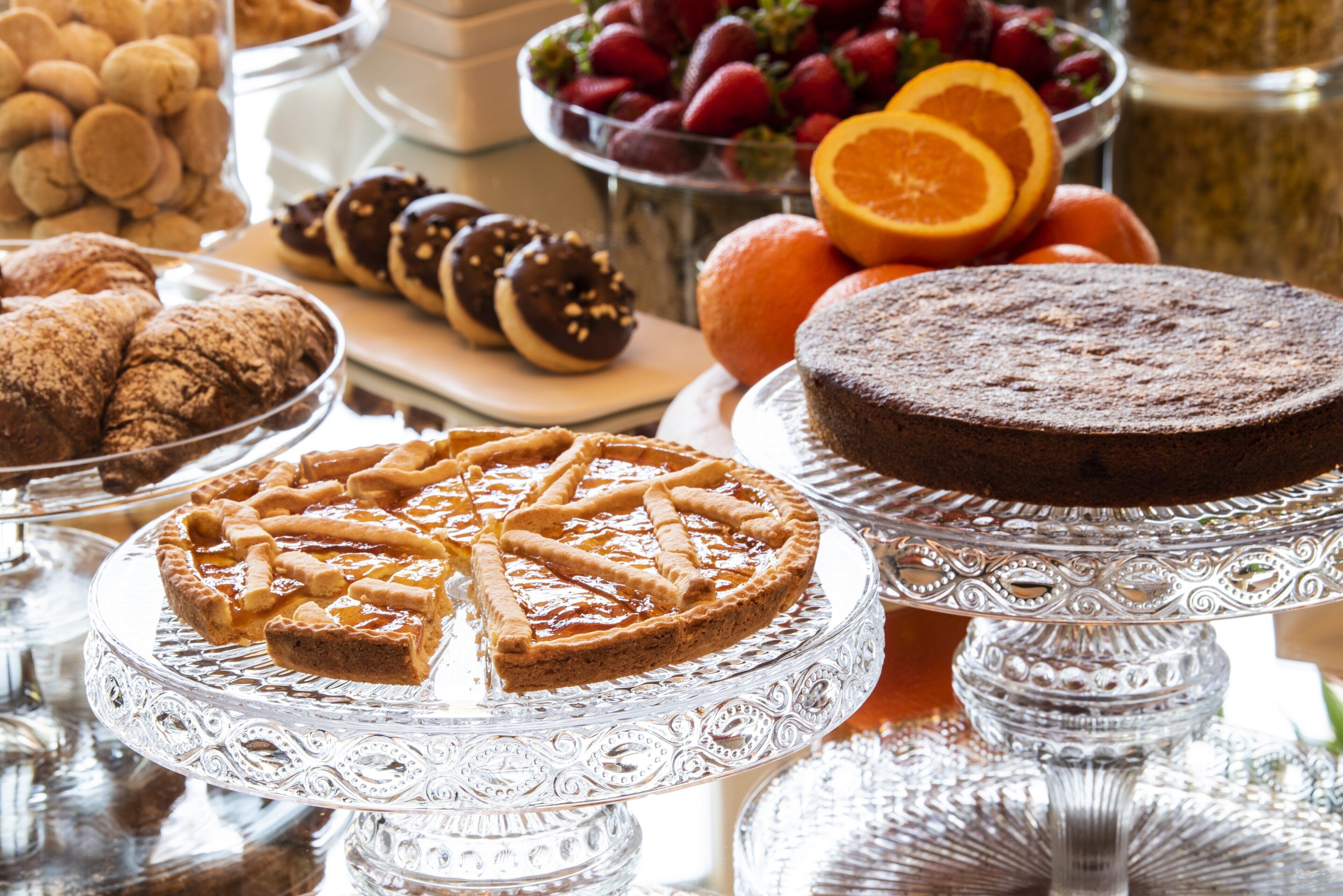 A variety of desserts on display, including a pie, pastries, and fruit.