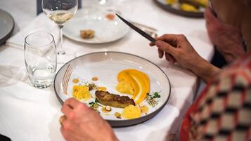A dining table with plates of food, a glass of water, and a wine glass.