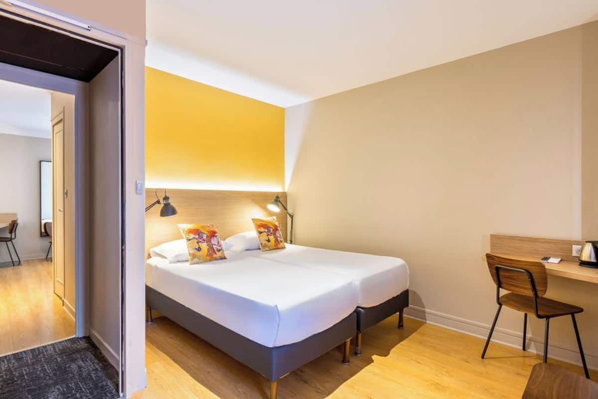 A modern hotel room with a large bed, a desk, and a chair.