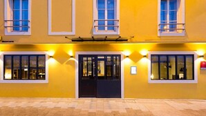 A yellow building with a black door and multiple windows, some with railings. - Hotel du Nord (Mâcon)