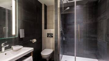 Un bagno moderno con cabina doccia in vetro, lavandino bianco e servizi igienici.