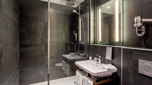 A modern bathroom with a glass-enclosed shower, a vanity with a sink, and a large mirror. - Hotel du Nord (Mâcon)