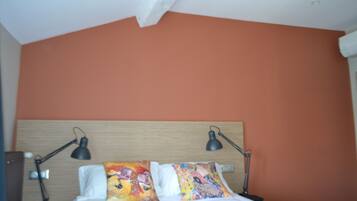 Een slaapkamer met een houten hoofdbord, twee bedlampjes en kleurrijke kussens.