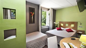 Una habitación de hotel con dos camas, una ventana con cortinas, un televisor y una pequeña mesa con lámpara.