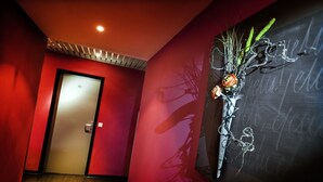 Un pasillo con una pared roja, una puerta y una obra de arte colgada en la pared que muestra una planta y texto.