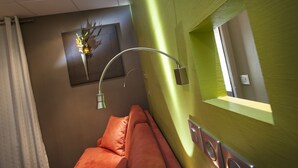 Un baño moderno con una pared de acento verde, una cortina de ducha, un perchero y una obra de arte enmarcada en la pared.