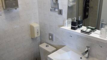 Een moderne badkamer met toilet, wastafel en douche.