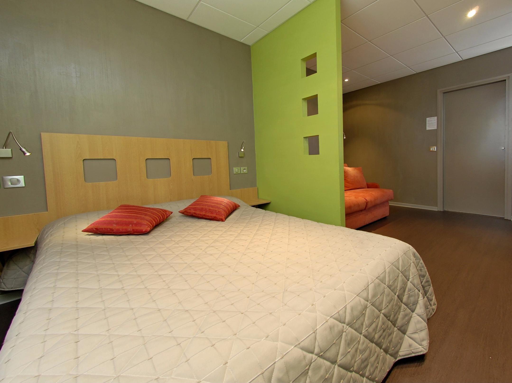 Een slaapkamer met een bed, een stoel, een deur en een muur met een groen paneel.