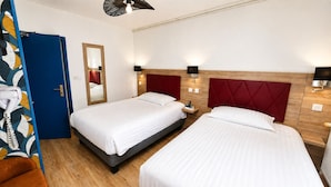 A hotel room with two beds, a mirror, bedside lamps, and a door with a towel hanging on it.