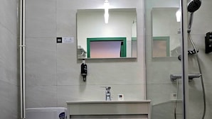 A bathroom with a toilet, a sink with a mirror, and a shower area.