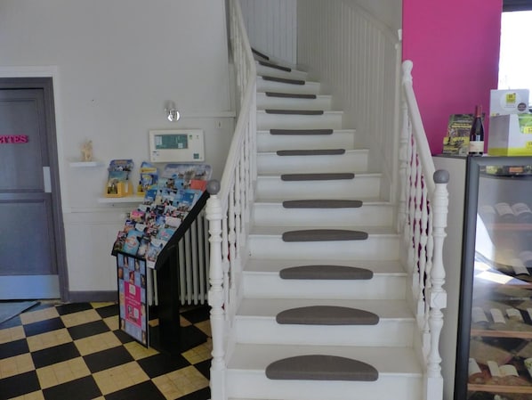 A staircase with white balusters and a checkered floor. - Logis Hôtel Au Croissant (Buzancais)