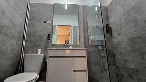Un baño moderno con inodoro, lavamanos y ducha.