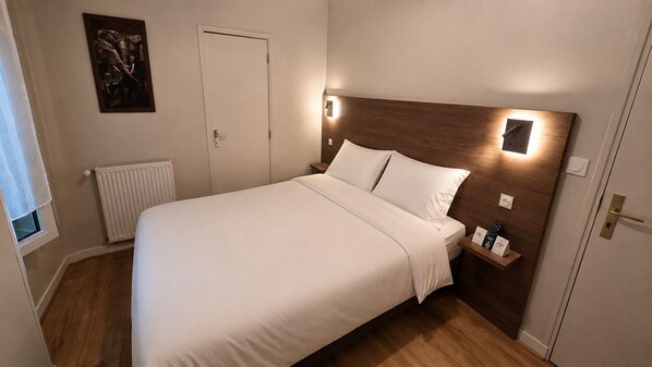 A bedroom with a bed, bedside table, wall-mounted light, and a door.
