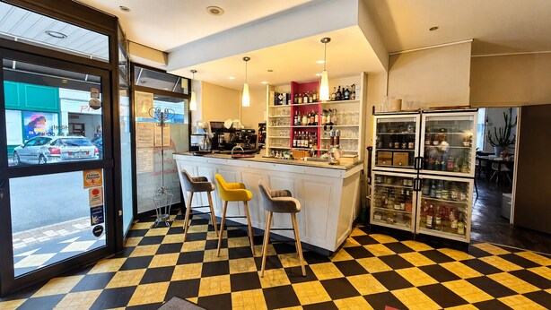 A bar area with stools, a counter, and a refrigerator stocked with beverages.