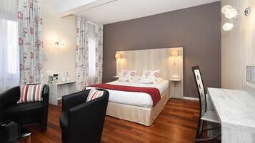 Ein Hotelzimmer mit einem Bett, zwei Stühlen, einem Schreibtisch und einem kleinen Tisch.
