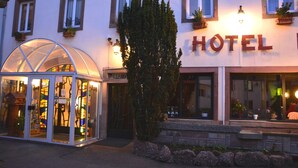 A hotel with a glass entrance, a sign reading "HOTEL", and potted plants on the windowsills. - Hôtel du Centre (Molsheim)